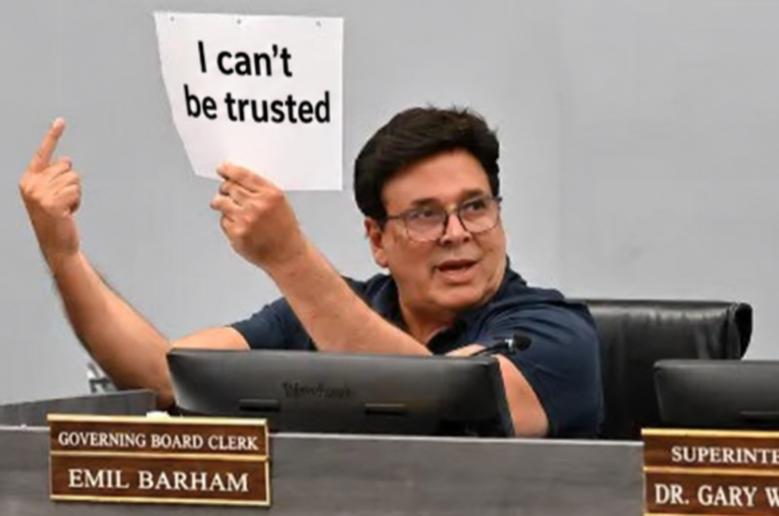 Emil Barham at a TVUSD board meeting holding up a sign reading I can't be trusted
